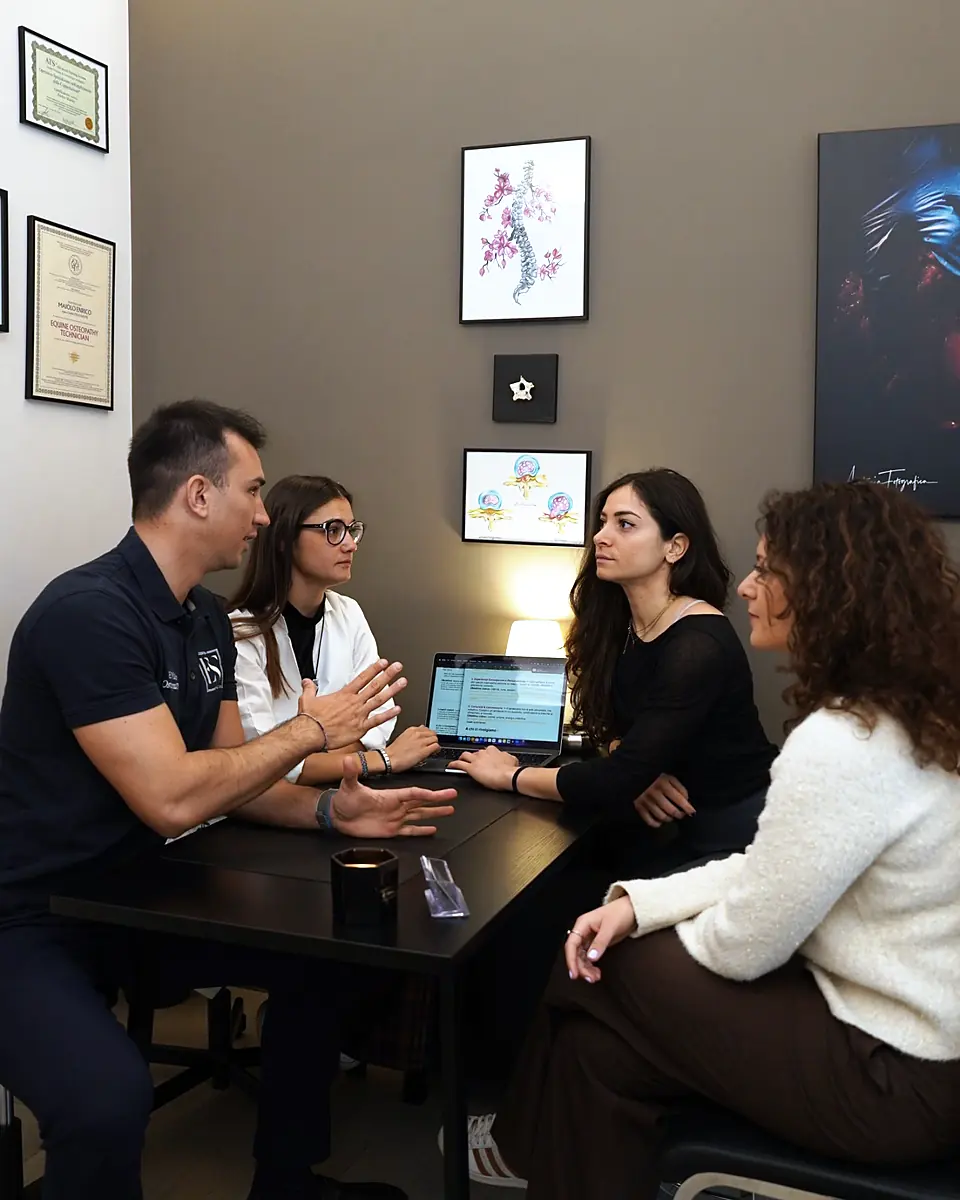 Quattro professionisti della rete parlano intorno a un tavolo, in uno studio, con un portatile aperto.