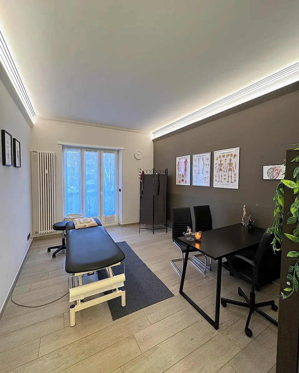 Uno studio di Via Salbertrand: lettino elettrico, scrivania con due sedie e tavole di anatomia alle pareti.