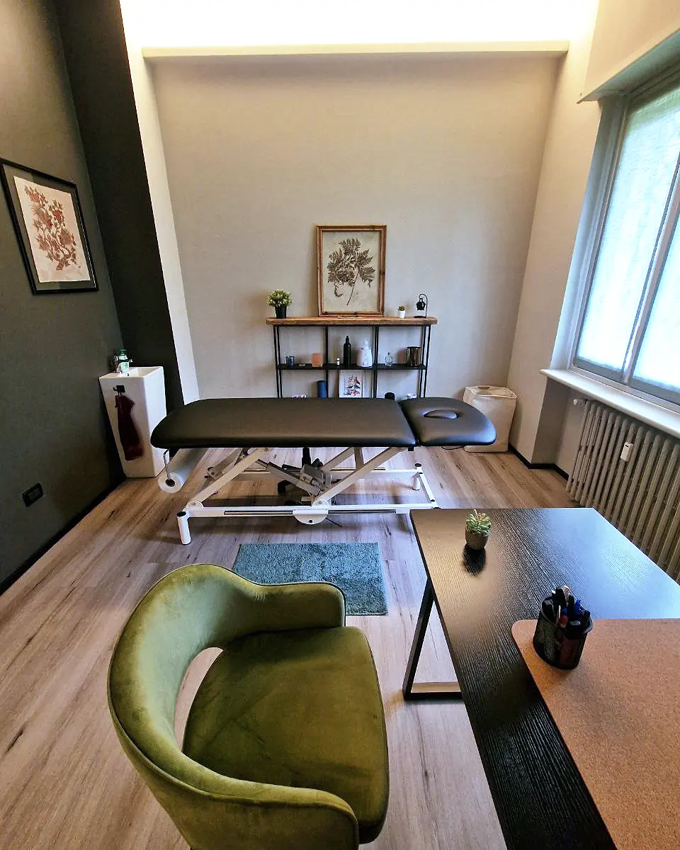 Uno studio di Via Sismonda con lettino elettrico, poltrona verde e scrivania vicino alla finestra.