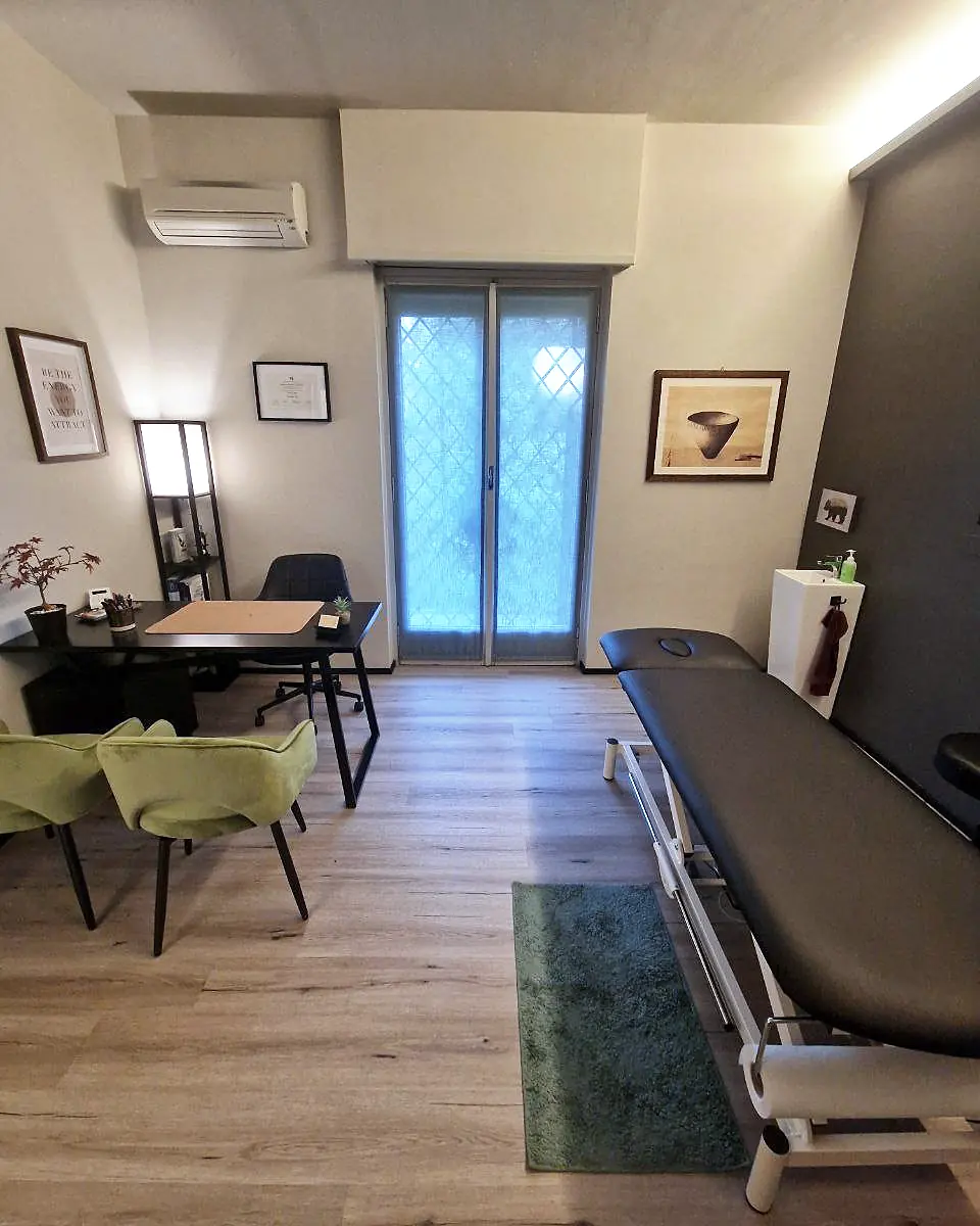 Uno studio di Via Sismonda: lettino elettrico, scrivania con sedie verdi e climatizzatore.